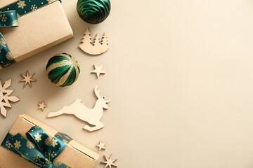 Authentic Christmas flat lay composition with craft paper gift boxes, wooden decorations, green balls on pastel beige background. Merry Christmas and Happy New Year banner mockup.