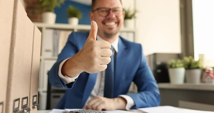Young smiling businessman sitting at table and showing thumb up 4k movie