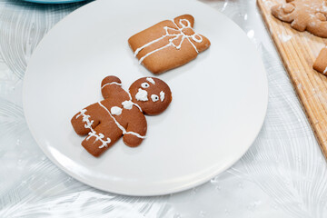 Gingerbread man and gift are on a white plate. The view from the top. The concept of holiday treats