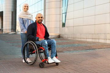 Muslim woman and man in wheelchair smiling and looking at camera