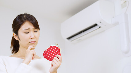 エアコンの電気代について考える女性..