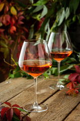 Autumn cozy romantic evening outdoors, wooden table with glasses with rose wine and grapes