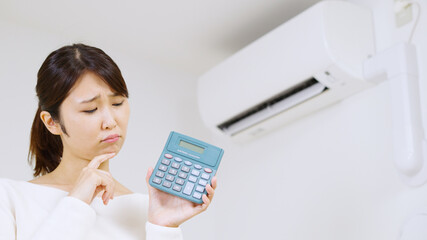 エアコンの電気代について考える女性..