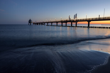 Obraz premium Sunrise at the beach at baltic sea with pier, Zingst, Western-Pomerania, Germany 