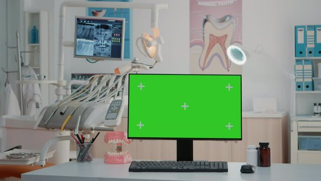 Nobody in dentist office with horizontal green screen on computer and equipment for oral care. Empty cabinet with chroma key and isolated mockup template on monitor for dentistry
