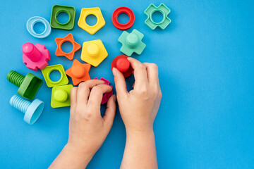 hands collect educational constructor for children, nuts and bolts in the form of geometric shapes