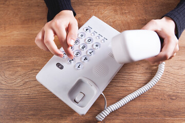 a woman dials a number on a home wired phone