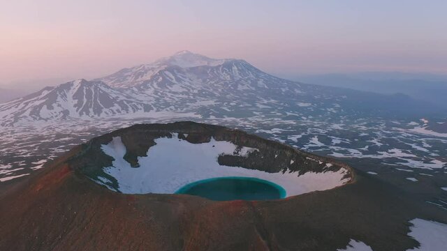 Aerial view of Gorely volcano, Kamchatka. Blue lake inside a crater on a snow-capped mountain top