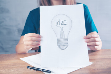 woman draws a light bulb with the inscription idea