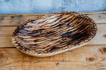 Kitchen equipment made to order, made of natural material. Wooden plate of oval shape with an unusual scorched texture. High-quality and unusual dishes.