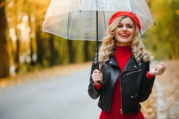 Beautiful girl with umbrella at autumn park.