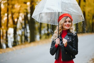 woman with umbrella walking at the rain in beautiful autumn park.