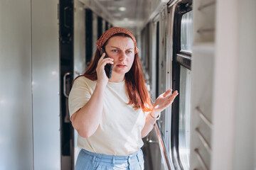 Fototapeta na wymiar A beautiful hipster woman with smartphone travelling on the train in Europe. Tourist travel concept. Freelancer goes on an independent journey