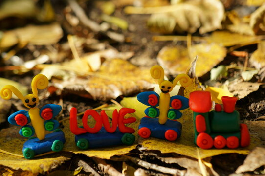 A toy train with fairy-tale characters and the inscription love. Against the background of autumn leaves.