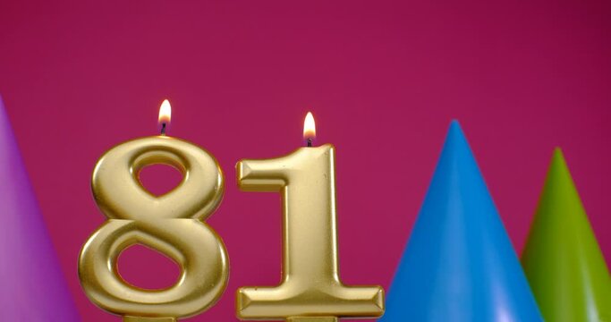 Burning birthday cake candle number 81. Happy Birthday background anniversary celebration concept. Birthday hat in the background