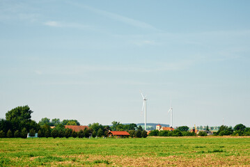 Fototapeta na wymiar Small european village with residential houses near wind turbine generator in summer day, Green renewable energy concept