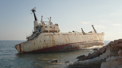 Abandoned old boat covered with rust ran aground on seaside. Neglected ship on water. Transportation concept.