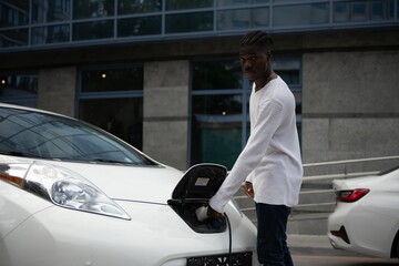 African American man charging his electric car.