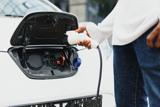 African American man charging his electric car.