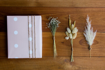 Pink gift box set of flowers on wooden table. 
