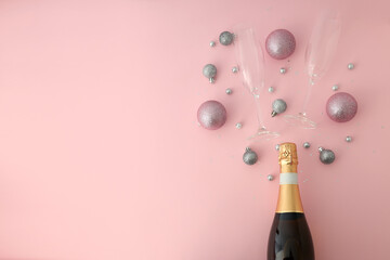 Bottle of champagne, glasses and baubles on pink background