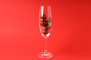 Champagne glass with baubles on red background