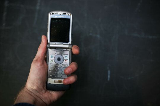 Minsk, Belarus - November 21, 2019: phone is held in hands against a dark background, Motorola RAZR V3, the slim flagship phone of 2004.