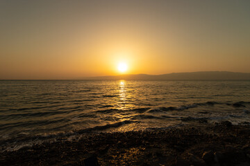 Amazing colors of sunrise over a wild and natural beach in the Dead Sea against the backdrop of the Jordan Mountains