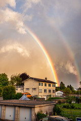 Beautiful double rainbow with European houses and cloudy sky in Cossonay, Switzerland