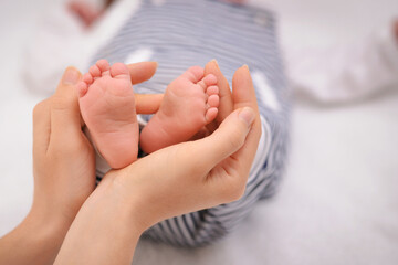 Close Up newborn baby feet while the mother is carrying in the home. Child foot in mom's hands. Happy family and breastfeeding concept. Beautiful conceptual image of maternity. Copy space