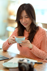 Young female relaxing, sipping, drinking coffee for afternoon at coffee shop.