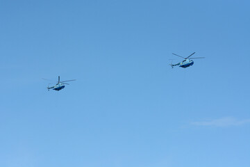 Military helicopters flying in a blue sky with flags. Military parade to the Independence Day.