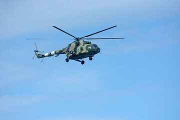 Military battle helicopter flying in a blue sky