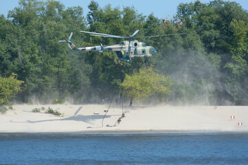 Military helicopter disembarking soldiers of Seaborne special forces on sandy beach attacking...