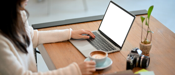 Female freelance photographer or cafe blogger working and writing a cafe review on her laptop