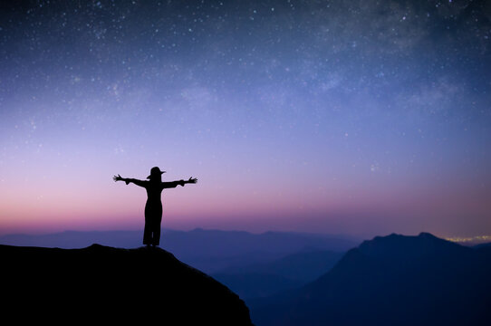 Silhouette of young female standing with both hands above your head watched the star and milky way alone on top of the mountain. She enjoyed traveling and was successful when he reached the summit.
