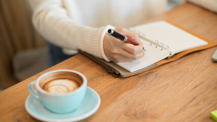Female in white sweater writing or taking notes something on her notebook