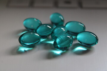 Blue liquid gel capsules on silver-colored laptop computer