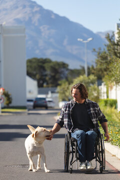 Caucasian disabled man with dog sitting on wheelchair on the road