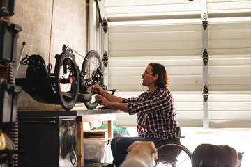 Caucasian disabled man sitting on wheelchair repairing another wheelchair at home