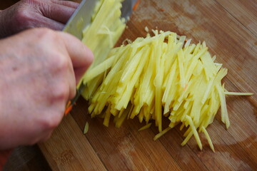 Cut potato shreds on kitchen chopping board