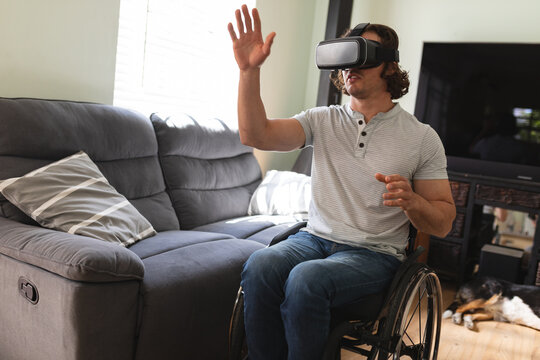 Caucasian disabled man sitting on wheelchair wearing vr headset and gesturing at home