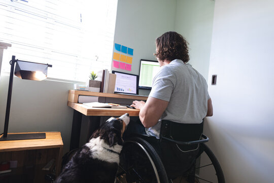 Caucasian disabled man sitting on wheelchair using laptop working from home
