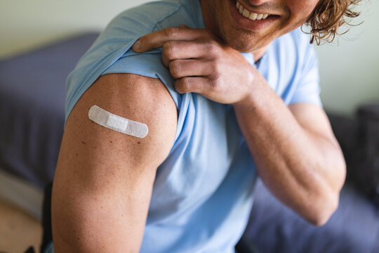 Mid section of caucasian disabled man showing his vaccinated shoulder at home