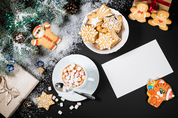 Christmas and New Year decoration composition. Top view of fur-tree branches on dark background with place for your text. Cups of fragrant coffee with marshmallows, gingerbread and chokolate.