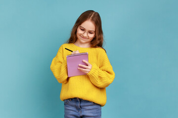 Portrait of positive little girl writing in notebook, smiling, notes, school child doing homework,...