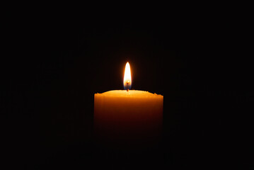 One single light candle burning brightly in the black background.Spiritual candle yellow flame....