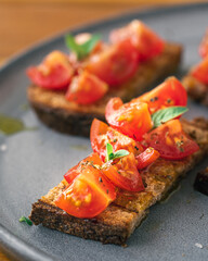 Tomato bruschetta served on plate with extra cherry tomatoes and toasted bread