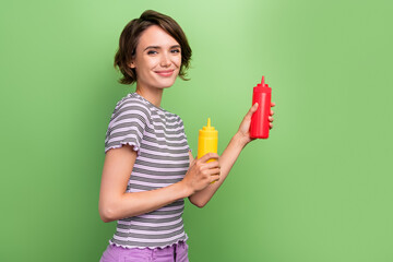 Photo of sweet charming young lady wear striped t-shirt smiling cooking empty space isolated green color background