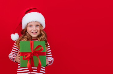 Christmas banner child in a santa hat holding a gift on a red background with place for text